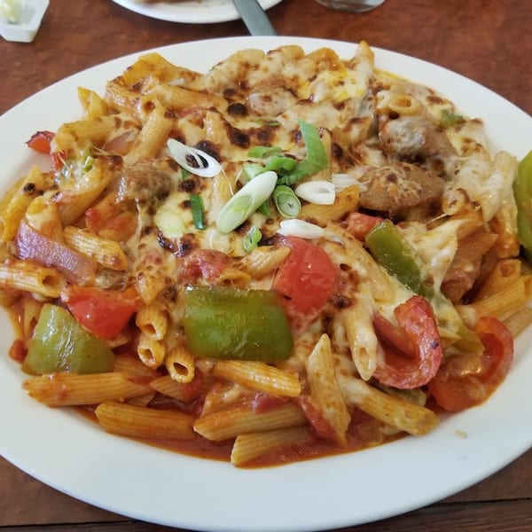 A close-up of Baldo's baked penne pasta with melted cheese, red and green peppers, and sausage.