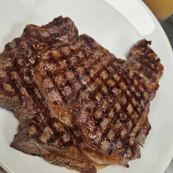 Grilled steak with prominent grill marks and glistening juices on a white plate at Baldo's Restaurant.